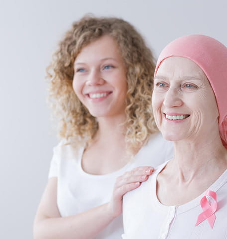 Een patiënt met een chemo mutsje op. Zij lacht.