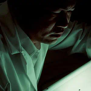 Fu-Kuen Lin examines x-ray film to identify gene coding for erythropoietin. The black areas show bacterial colonies containing the gene.