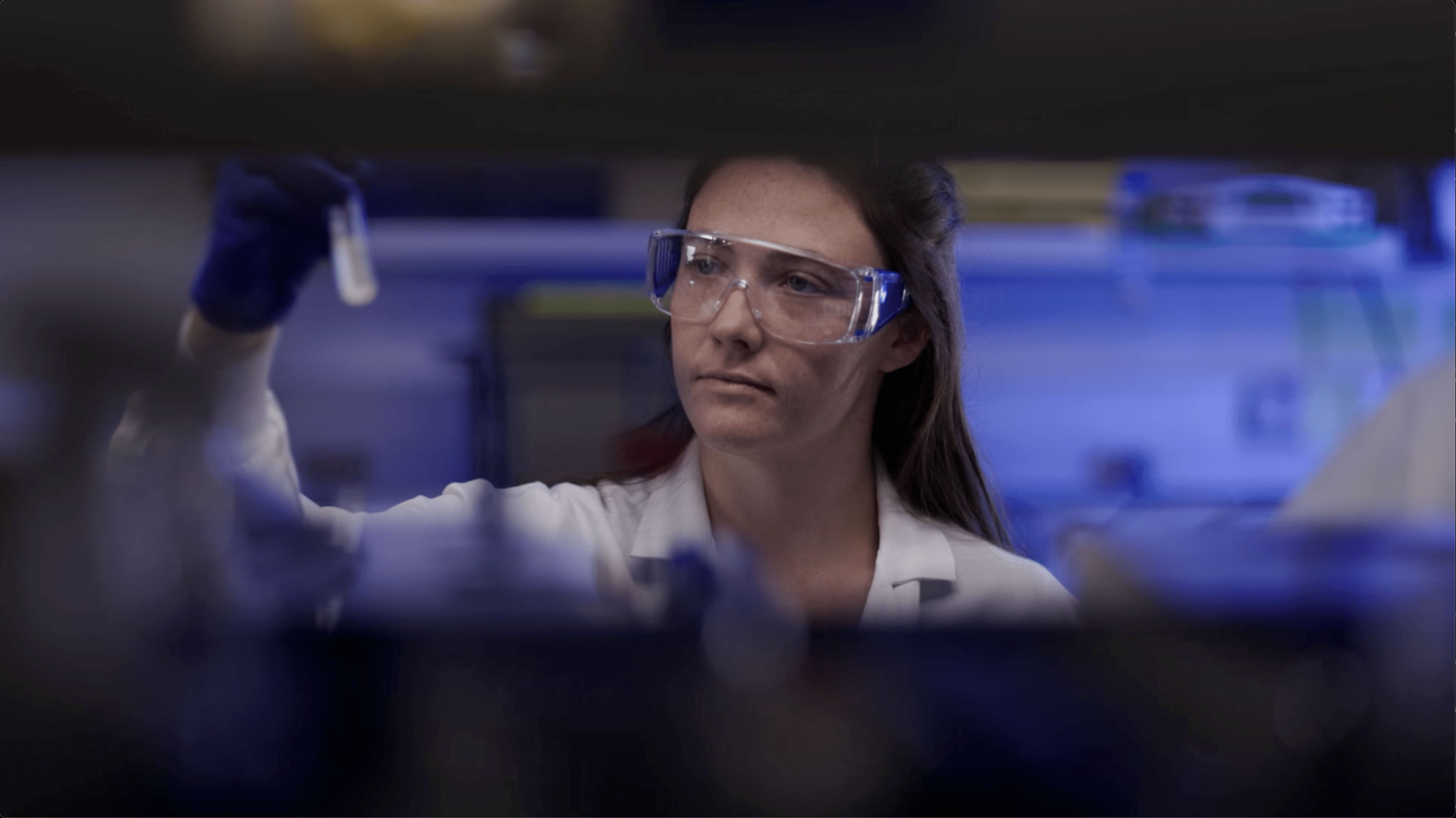 Amgen scientist conducting biotechnology research, carefully examining a test tube in the lab.