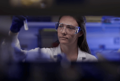 Amgen scientist conducting biotechnology research, carefully examining a test tube in the lab.