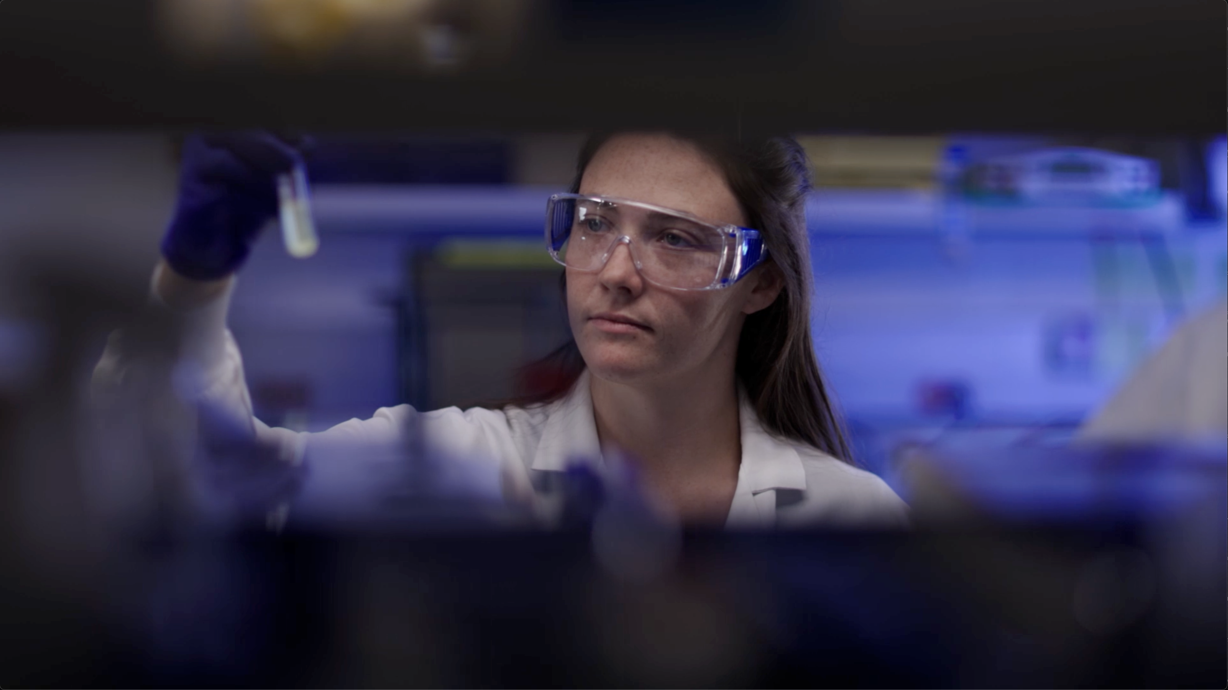Amgen scientist conducting biotechnology research, carefully examining a test tube in the lab.