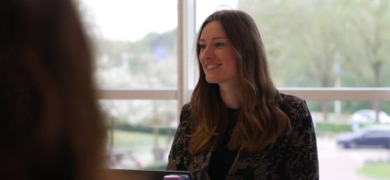 Luna Engelschman in gesprek met een collega in een vergaderruimte bij Amgen.