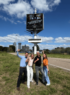 Het team bij een reclamebord langs de snelweg in Rotterdam